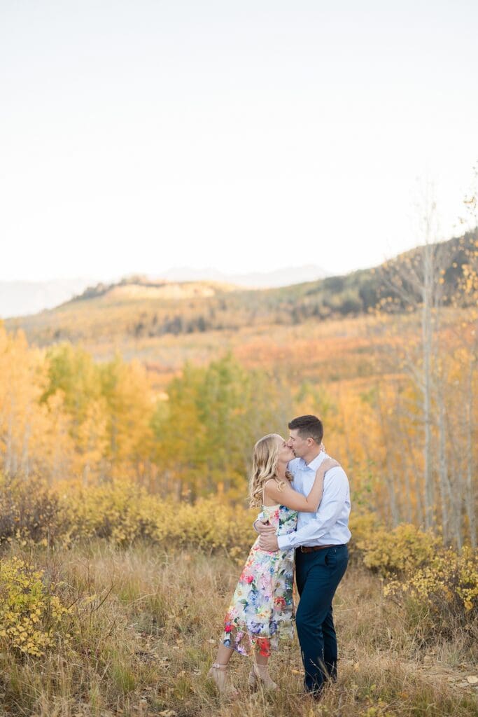 Couple kissing in golden aspen trees during a fall engagement session at Bonanza Flat near Park City, Utah