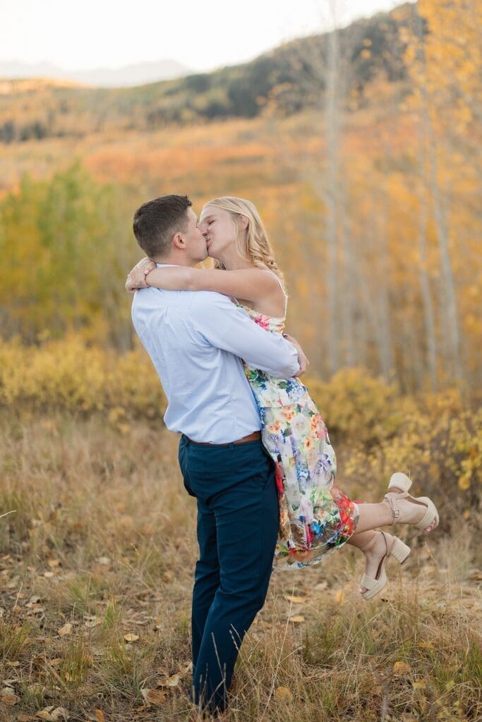 Couple kissing in golden aspen trees during a fall engagement session at Bonanza Flat near Park City, Utah