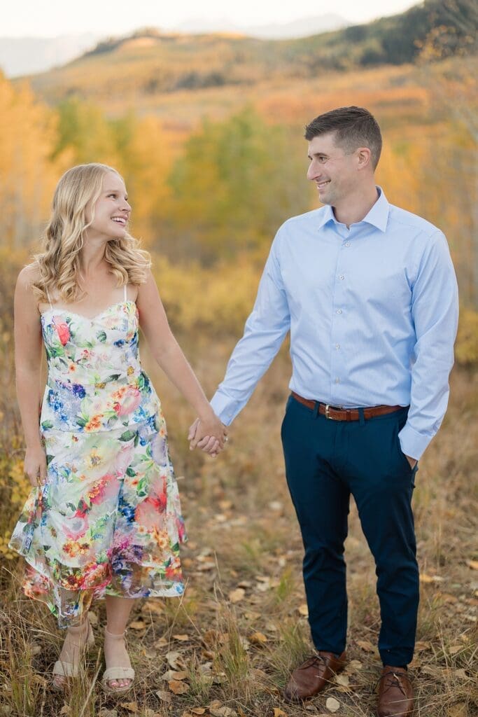 Couple walking through golden aspen trees during a fall engagement session at Bonanza Flat near Park City, Utah